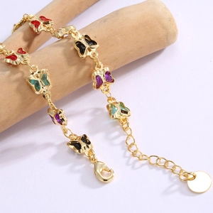 Gold plated brass bracelet with colorful acrylic butterfly charms on a wooden stand