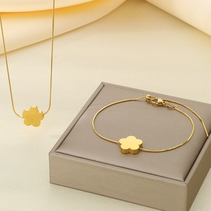 Detail of gold clover necklace and bracelet set displayed on a grey jewelry box