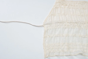 Vue détaillée des volants superposés et du cordon sur un ensemble jupe longue beige