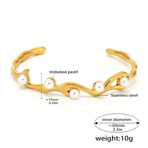 Macro detail of wave-shaped 18K gold-plated stainless steel cuff with imitation pearls