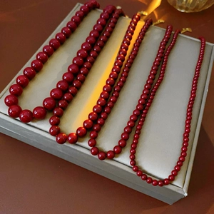 Detailed view of four red beaded necklaces with gradient sizes on a beige display tray