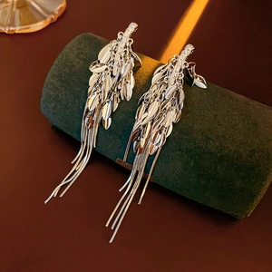 Detail of silver leaf tassel earrings displayed on a dark green jewelry stand