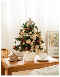 Detail of a mini Christmas tree in a white metal bucket with warm LED lights and pine cones