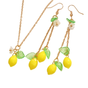 Detail view of summer lemon jewelry set with yellow fruit charms and green leaves