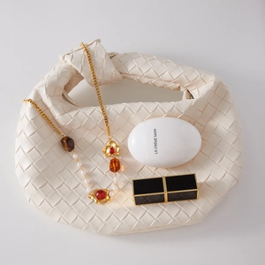 Macro della collana vintage in resina e perle in borsa di pelle intrecciata con catena oro