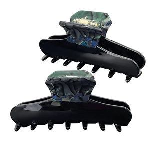 Close-up of elegant black hair claws with green-blue marbled acetate accents and metal springs