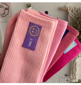 Gros plan sur des chaussettes en coton rose avec étiquette Smile et détails