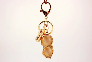 Detail of gold metal peanut keychain with cat eye stones and sparkling rhinestones