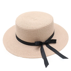 Gros plan d'un chapeau de paille beige à sommet plat avec ruban en gros-grain noir