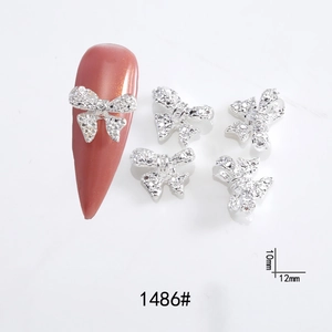 Macro view of silver metal bow nail charms with rhinestones, size 10mm x 12mm