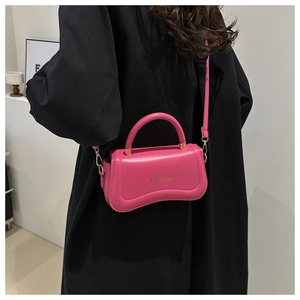 Detail of rose pink handbag with unique wave base design and gold fashion text