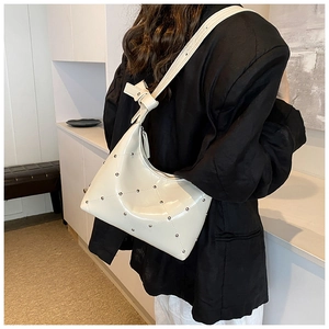 Détail du sac à bandoulière en cuir PU blanc cassé avec clous argentés sur blazer noir