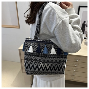 Detailed close-up of woven geometric patterns and blue tassels on a tote bag