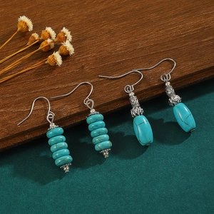 Bohemian turquoise drop earrings with vintage silver hooks on a natural wooden background