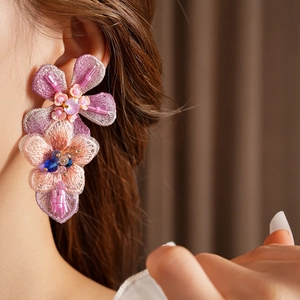 Close-up of pink gradient embroidered floral earrings with beads on model