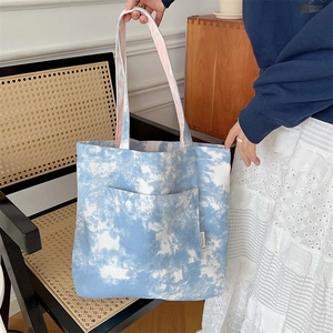 Dettaglio della borsa tote in tela tie-dye con tasca frontale e texture artistica blu