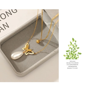 Detail view of 14K gold double-layer necklace with butterfly and pearl pendants in a box