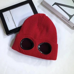 Detail view of red knitted beanie with built-in dark oval lenses and thick ribbed texture