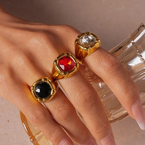 Macro detail of high-polish gold rings featuring square-cut red, black, and clear gemstones