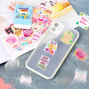 Detailed view of pink motivational stickers on a mobile phone case and notebook