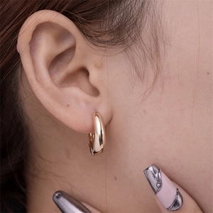 Detailed view of polished gold geometric hoop earring worn on a model earlobe