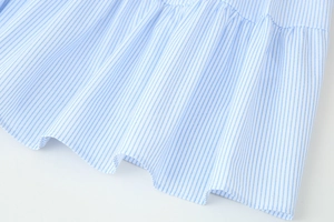 Detailansicht des Rüschensaums und des blau-weiß gestreiften Stoffes des Kleides