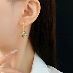 Detail of vintage gold-plated flower earring with colorful enamel and zircon on a model