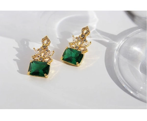 Close-up of vintage emerald green rectangular stone earrings with golden zircon crown