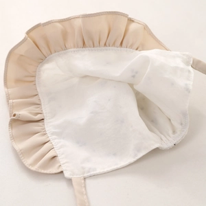 Dettaglio di cappello da sole per neonata con bordi a balze e fodera a pois cuori
