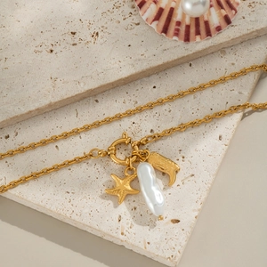 Chic gold starfish and pearl pendant necklace on stone background for beach fashion