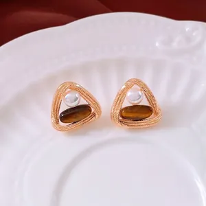 Vintage gold twisted triangle earrings with tiger eye stone and pearl on a white plate