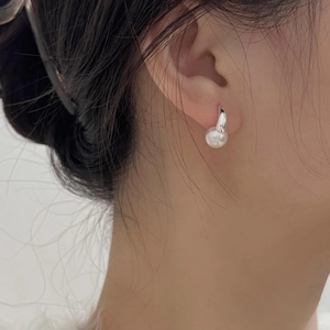 Close-up of minimalist 925 sterling silver pearl earrings worn on a model ear