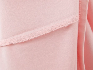 Gros plan sur la texture du tissu rose et les coutures précises de la robe sans manches