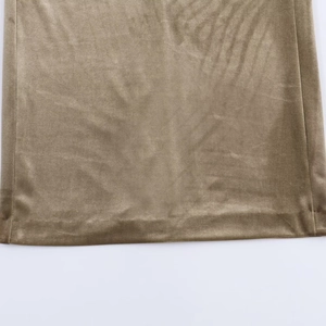 Close-up of bronze gold velvet dress showing high-shine fabric texture and hem stitching