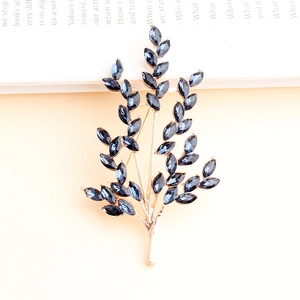 Golden wheat ear brooch with deep blue crystals on a minimalist vintage background