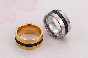 Detail of minimalist gold and silver wide bands with black geometric pyramid inlay