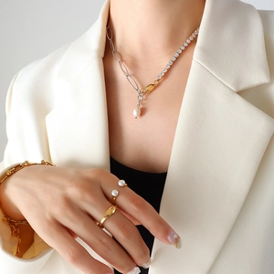 Necklace with two-tone chain and pearl pendant plus matching rings worn by a model