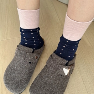 Close-up of navy and pink polka dot knitted socks paired with brown wool felt clogs