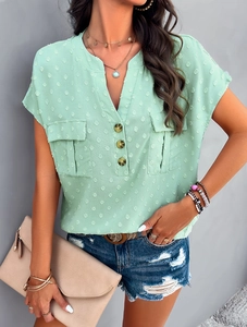 Detail of mint green V-neck blouse with textured polka dots and functional front pockets