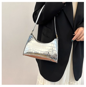 Chic silver crocodile embossed baguette bag worn by model on a grey studio backdrop