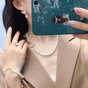 Elegant white freshwater pearl jewelry set with gold butterfly charms on a model