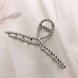 Detailed close-up of large silver metal hair claw clip with twisted rope texture design