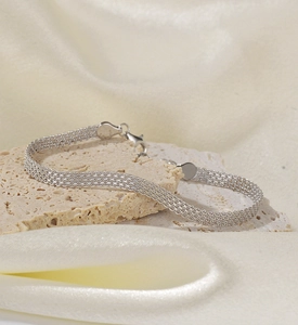 Macro detail of multi-layer mesh woven S925 sterling silver bracelet on mineral stone