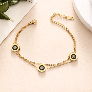 Detail of gold double-layer chain bracelet featuring black enamel rings and zircon stones