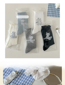 Détail de chaussettes côtelées brodées chat en crème, bleu, gris, blanc et noir