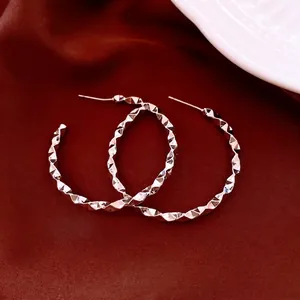 Silver geometric faceted C-shaped hoop earrings on elegant dark red silk background