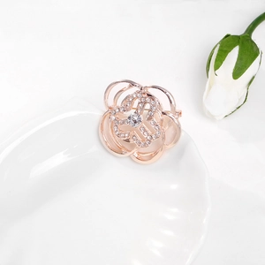 Macro detail of a rose gold floral brooch with sparkling rhinestones on a white surface