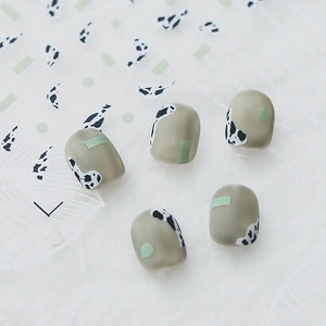 Matte press-on nails in bean paste green with minimalist cow print and geometric patterns