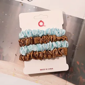 Set of four satin scrunchies in light blue and bronze on white cardstock