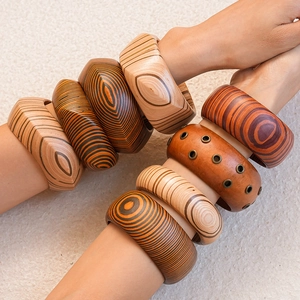 Detail of stacked wooden bracelets with geometric patterns and natural textures